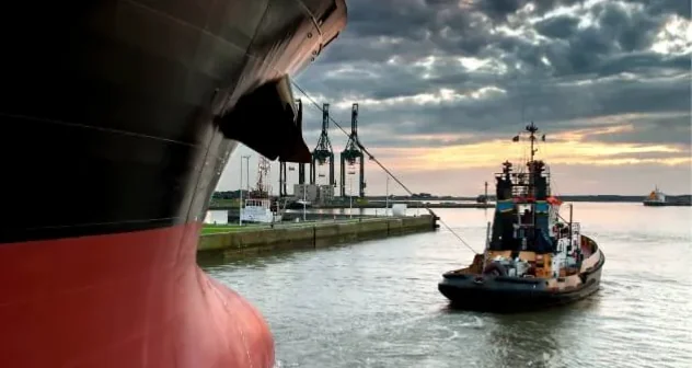 Cargo vessel and tugboat operating in an industrial port